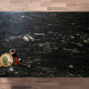Overhead view of Cosmic Black Granite worktop showing bold natural veining and mineral movement, photographed from above with a small styled tray in the corner.