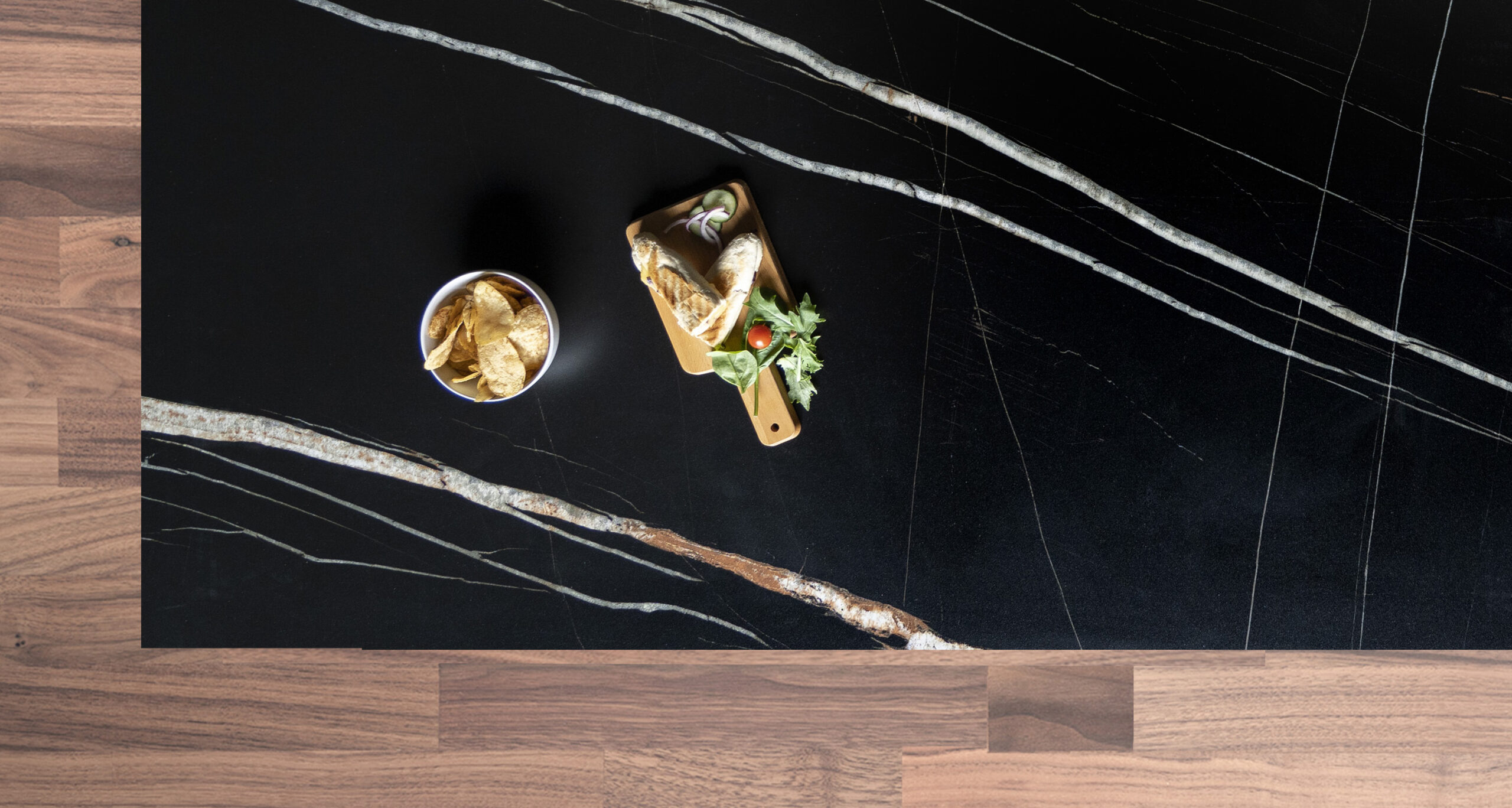 Noir St Laurent Porcelain worktop slab close up showing deep black surface with bold gold veining, styled with food and accessories