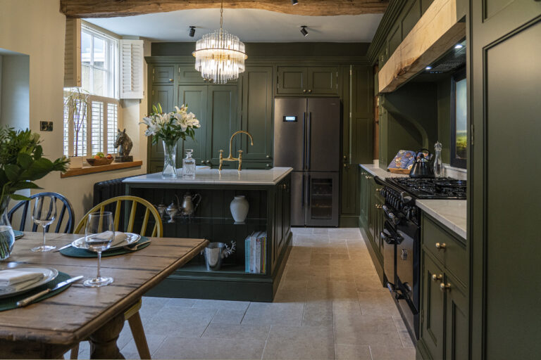 Gold Calacatta worktops in a traditional kitchen with green cabinetry and chandelier lighting