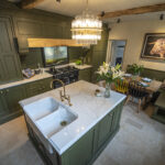 Traditional kitchen with Gold Calacatta island, green cabinetry and chandelier lighting