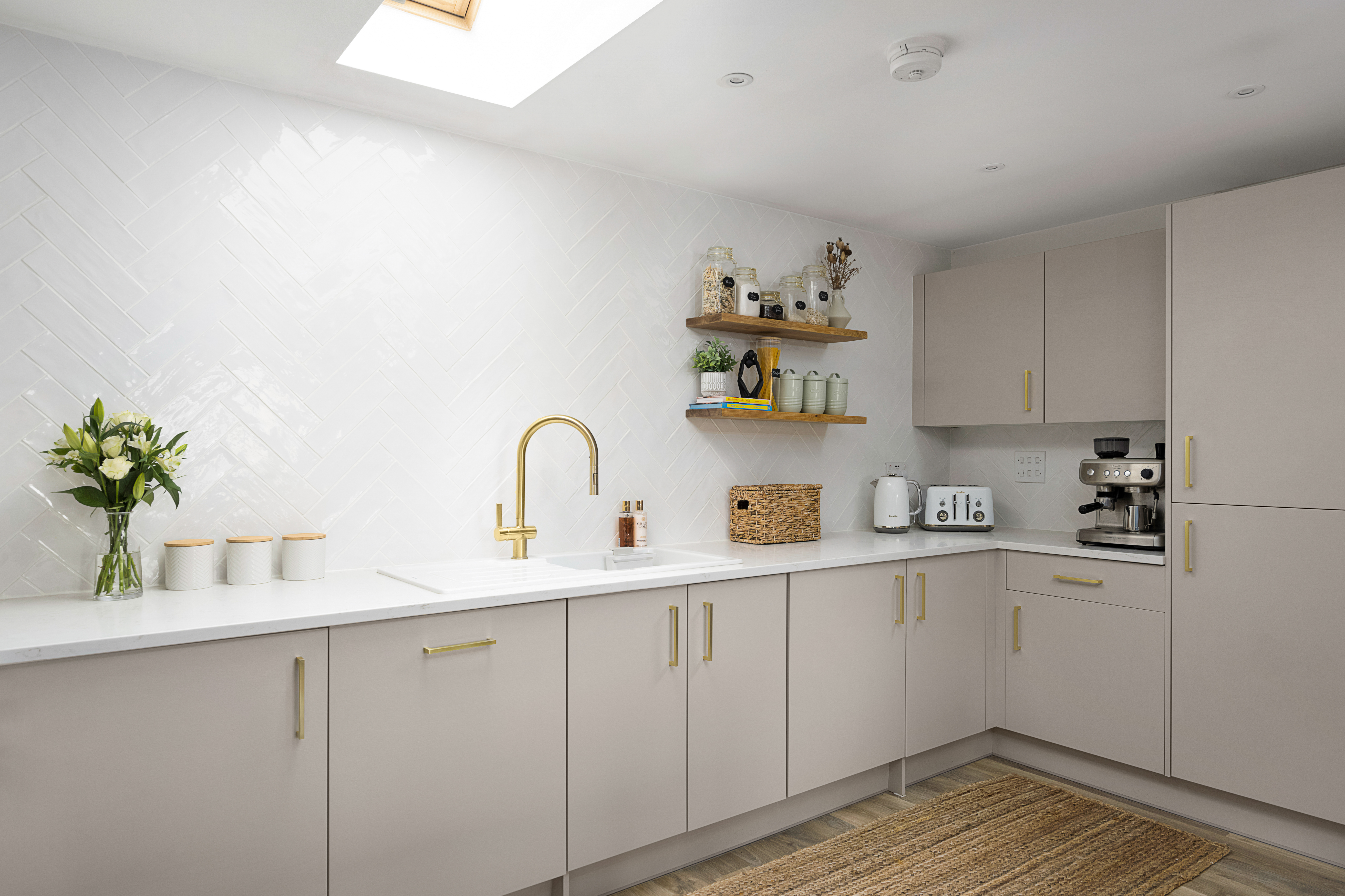 Modern kitchen fitted with Carrara Quartz worktops and brass accents