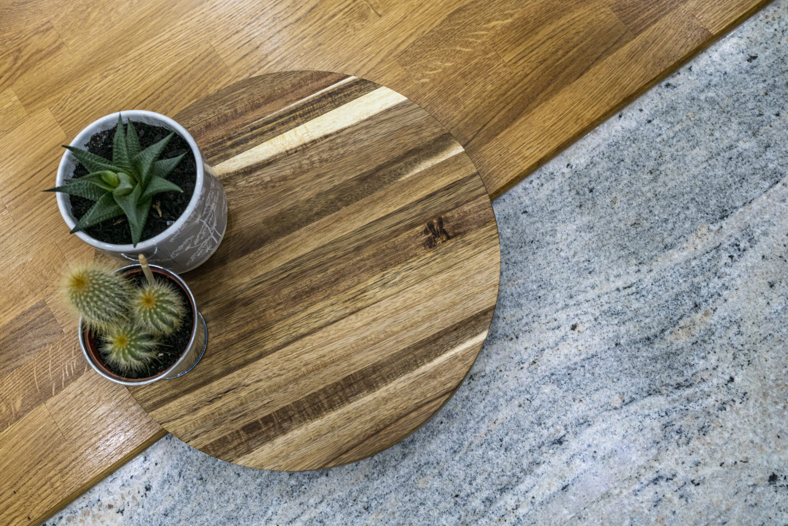 Styled close up of an Ivory Fantasy Granite worktop with a wooden board and small plants, showing the Granite colour and surface detail.
